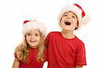 Laughing christmas kids looking aside, wearing santa hats