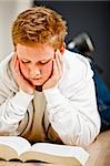 Boy lying in the floor reading books from school