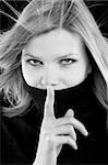 young beautiful blonde girl in a black turtleneck is requesting silence. black and white image