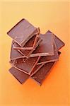 Stack Of Dark Chocolate Pieces,  Over Orange Background