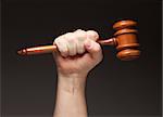 Male Fist Holding Wooden Gavel on a Grey Background.