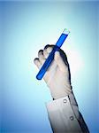 A scientist's hand holds a test tube filled with a blue liquid.