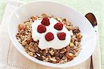 Healthy breakfast with muesli, raspberries and yoghurt in white bowl