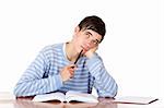 Young student is sitting on desk with open book and looks contemplative up.  Isolated on white.