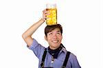 Asian Boy, dressed with Bavarian Lederhose holds an full Oktoberfest beer stein on his head. Isolated on white.