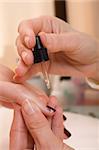 Moisteriser being applied to a womans finger nail.