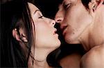 Young adult Caucasian couple in passionate emrace kissing each other during sexual foreplay