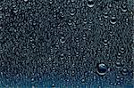 Water drops on a dark blue glass surface. Nature collection.