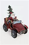 Statuette of Santa Klaus sitting in an old car on isolated background