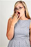 Portrait of a beautiful blonde woman with light blue eyes and classic make-up yawning on grey background