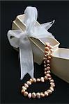 Small cream colored box with ribbon and pearl necklace