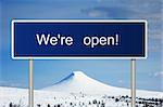 A blue road sign with white text saying We're open!