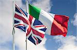 Italian and british flags on a pole moved by wind