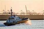 Pilot-boat passing by at high speed on the river in evening light - industry background with cranes