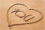 Heart shape symbol with the word you on sandy beach