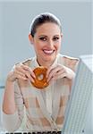 Young businesswoman eating a donut at her desk