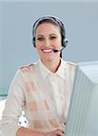 Charming businesswoman with headset on working at a computer in the office