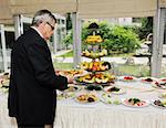 table on catering and buffet party on business seminar conference or wedding with man who choosing meat for eat and bring it in dish