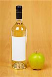 A bottle of cider and apple on a wooden table