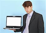 The serious businessman holds on a hand the laptop on a blue background