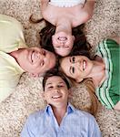 Portrait of happy family lying on carpet with their heads close together and smiling.