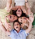 Portrait of happy family lying on carpet with their heads close together and shouting
