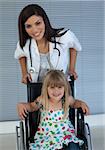 Portrait of a little girl on a wheelchair and a young doctor in the hospital