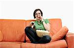 young woman eats popcorn, watching movies and eating popconr isolated on white