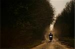A motorcycle and its rider are silhouetted on an off-road track in Romania