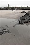 a rocky beach pool with castle on a warm day with a calm sea an ideal place to have a walk in ireland