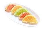 Group of sweets as citrus fruits on white plate. Isolated on white background. Close-up. Studio photography.