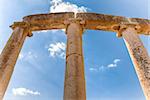 ancient roman columns against blue sky background with white clouds