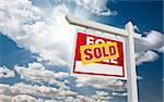 Sold For Sale Real Estate Sign over Clouds and Blue Sky with Sun Rays.
