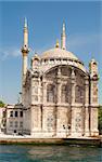 A mosque on the edge of a large river against a blue sky