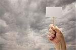 Man Holding Blank Sign Over Dramatic Storm Cloudy Sky - Ready For Your Own Message on Sign and Over Clouds.