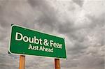 Doubt and Fear Just Ahead Green Road Sign with Dramatic Storm Clouds and Sky.