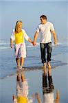 Happy couple stroll along the empty beach