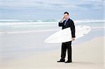 Business man in suit walking with surfboard on the beach