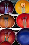 Decorative bowls and flatware are on display for sale at a market. Vertical shot.