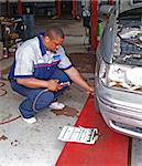 Auto mechanic inspecting a car’s tire pressure in a service garage.