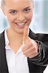 Young business woman showing OK sign, looking at camera and smiling. Focus on hand