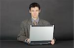 A young man working with laptop computer on a dark background