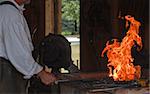 Blacksmith works on a heart trivet at the kiln