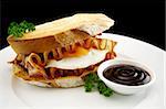 Curled bacon and egg sandwich with BBQ sauce ready to serve.