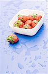 White plate with strawberry, on wet blue background
