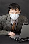 The young man in a medical mask works in the Internet