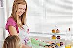 Positive young woman baking cookies for her girlfriend in the kitchen