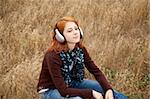 Young  smiling girl with headphones at field.