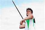 Handsome male athlete throwing a javelin outdoors