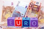 toy letters that spell euro against a cash background